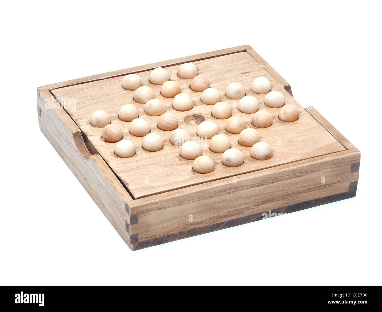 Wooden solitaire board with pieces shot over white Stock Photo