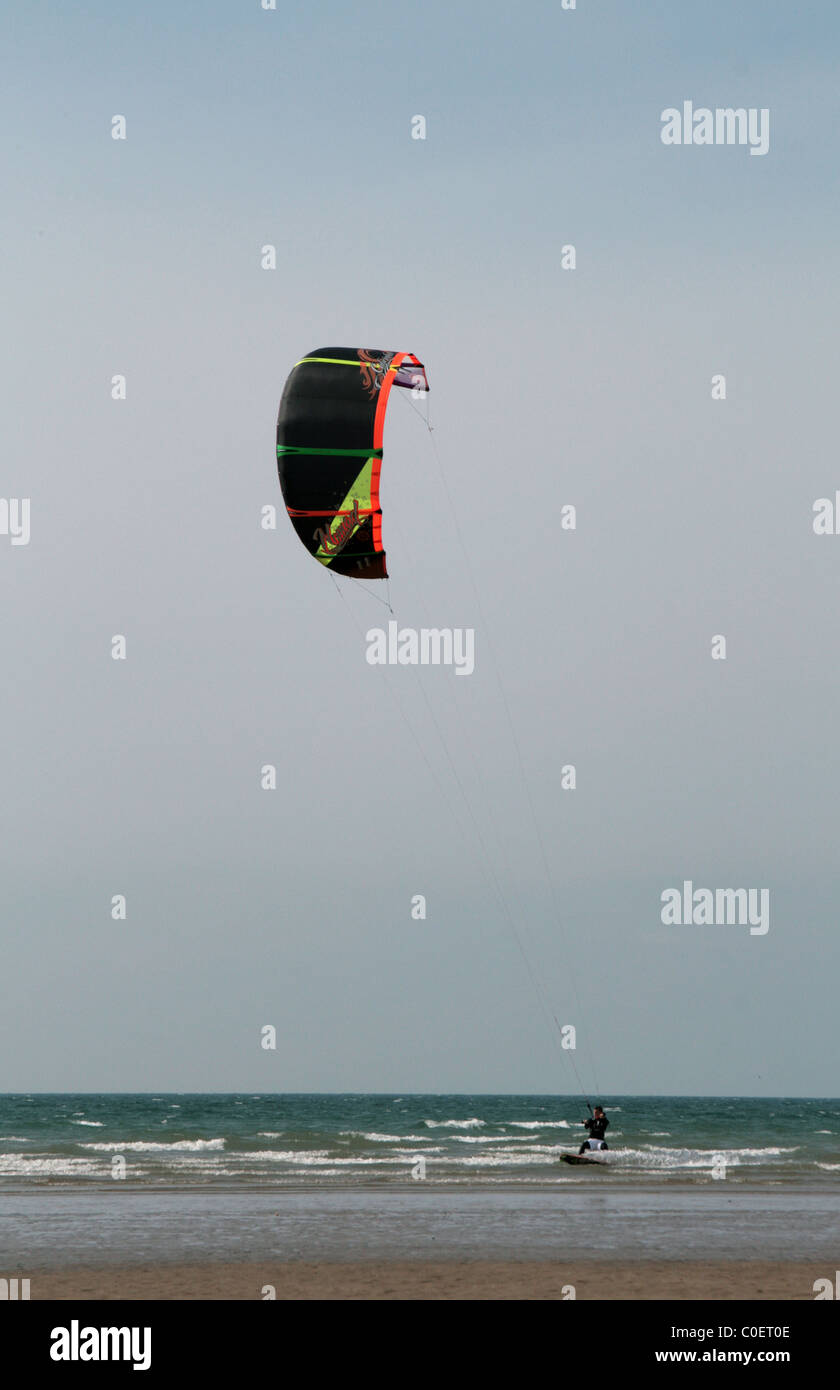Kite Surfer with a Bright Kite Skimming the Waves at Westward Ho! Devon, U.K. Stock Photo