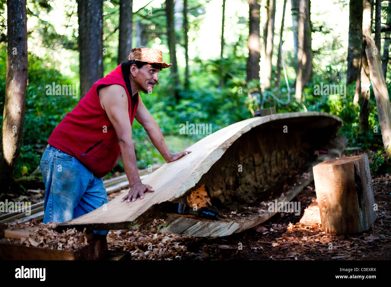 A man native to the West Coast of Vancouver Island carves a canoe as his tribes have for centuries. Stock Photo
