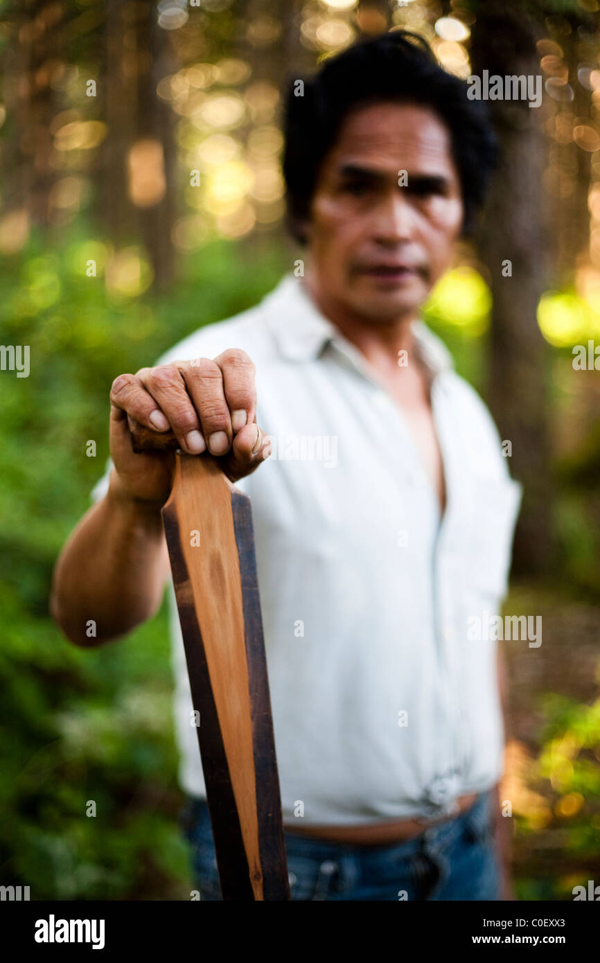 A portrait of a man native to the western coast of Vancouver Island holding a hand carved paddle. Stock Photo