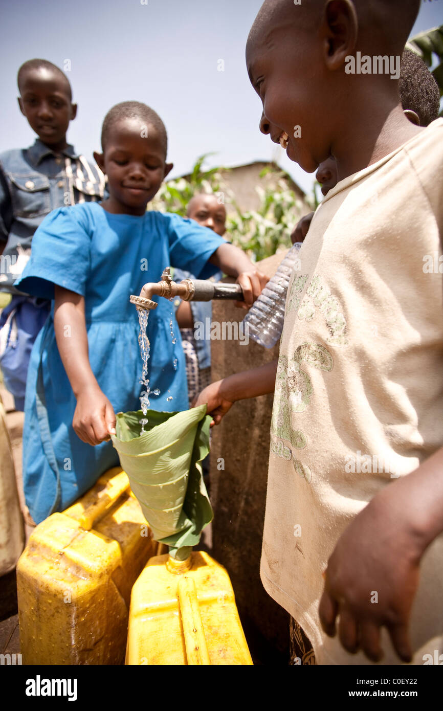 Girls filling water bottles at Rwandan village well Stock Photo - Alamy