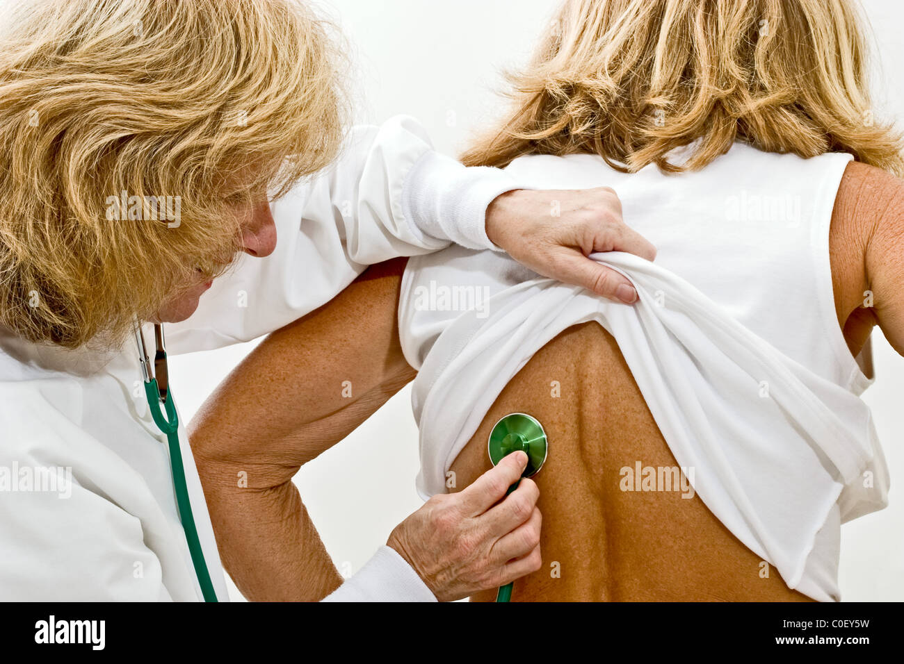 Female doctor checking the heartbeat of another woman with a stethoscope Stock Photo