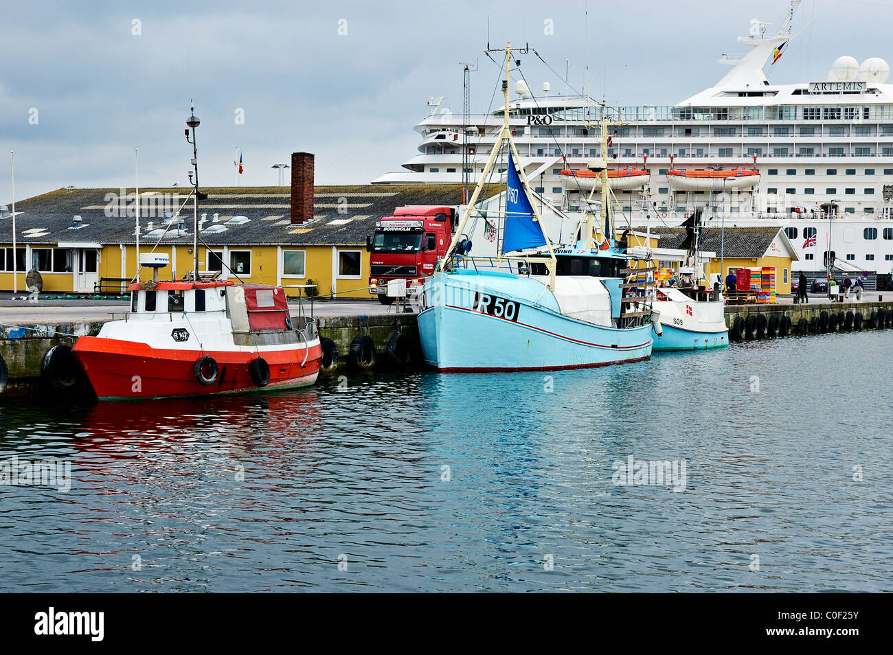 Fishing boats dwarfed by the P&O cruise ship Artemis moored in the port