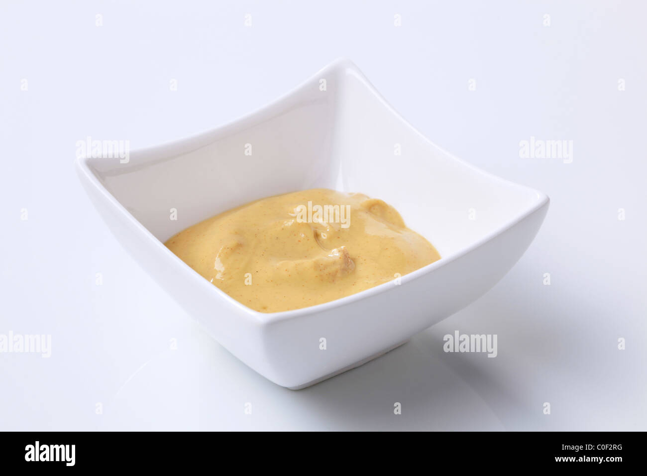 Spicy mustard in a small square bowl Stock Photo