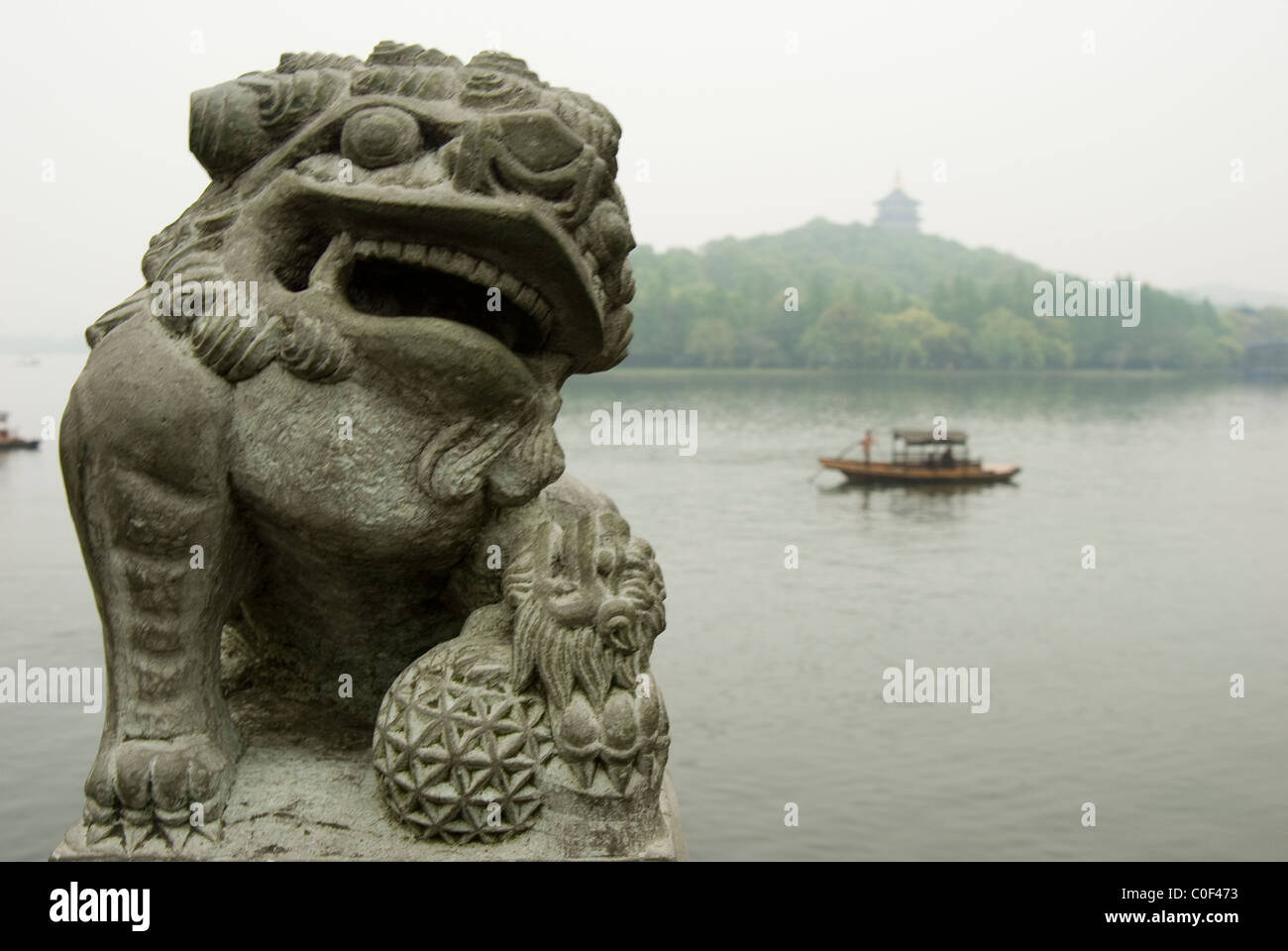 Statue of fu lion beside West Lake, Hang Zhou with Leifeng Tower and