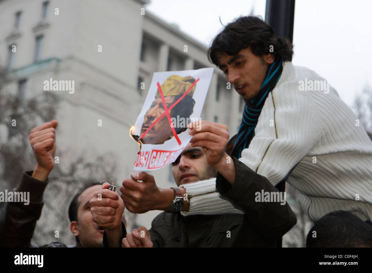 Protester lights a Gadaffi poster in London Stock Photo