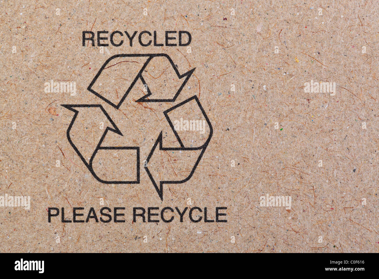 Close up photo of the recycle symbol printed on a recycled cardboard background. Stock Photo