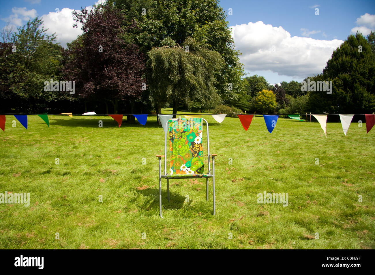 Colorful chair on a green grass with red, blue, green and white bunting Stock Photo