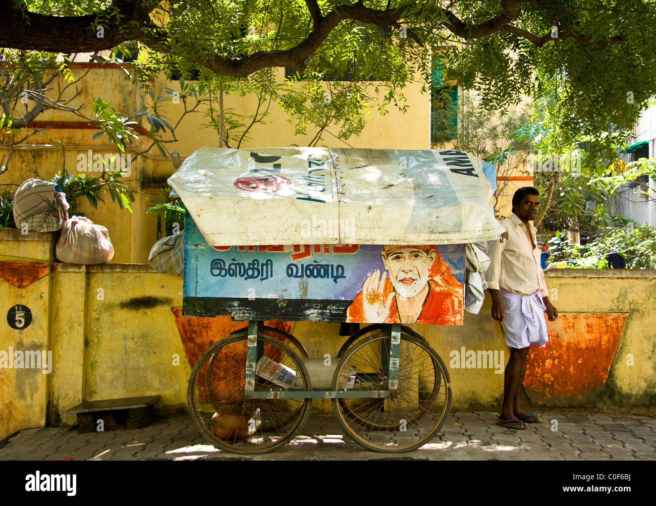 Indian ironing man with trolley under a tree. Stock Photo