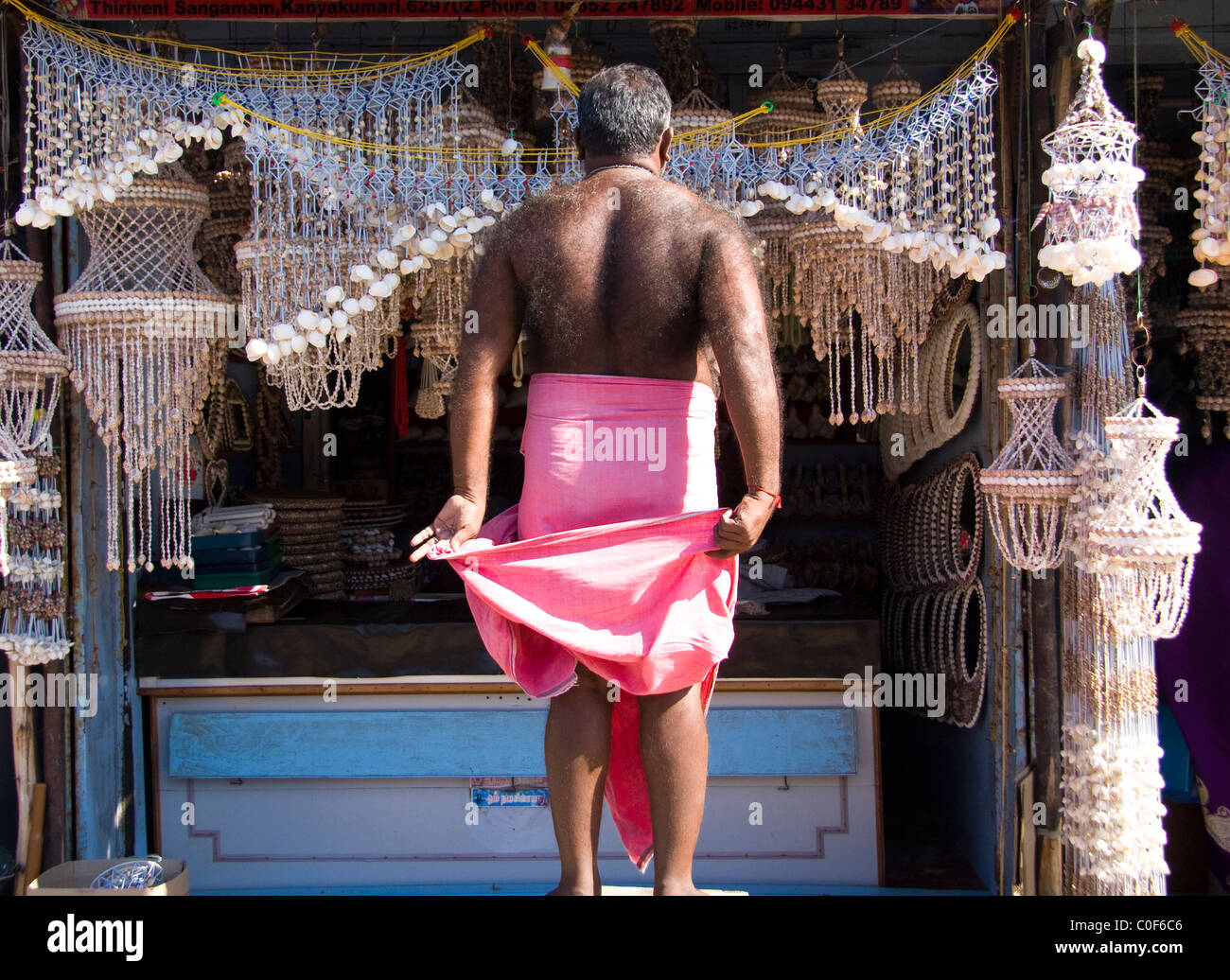 Indian hairy man with pink lunghi in front of his shell stall. Stock Photo