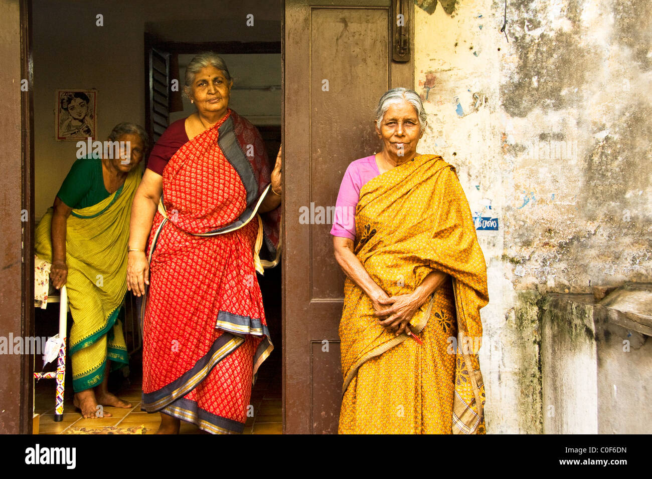 Three old Indian ladies dressed up with colorful saris in front of an old house. Stock Photo