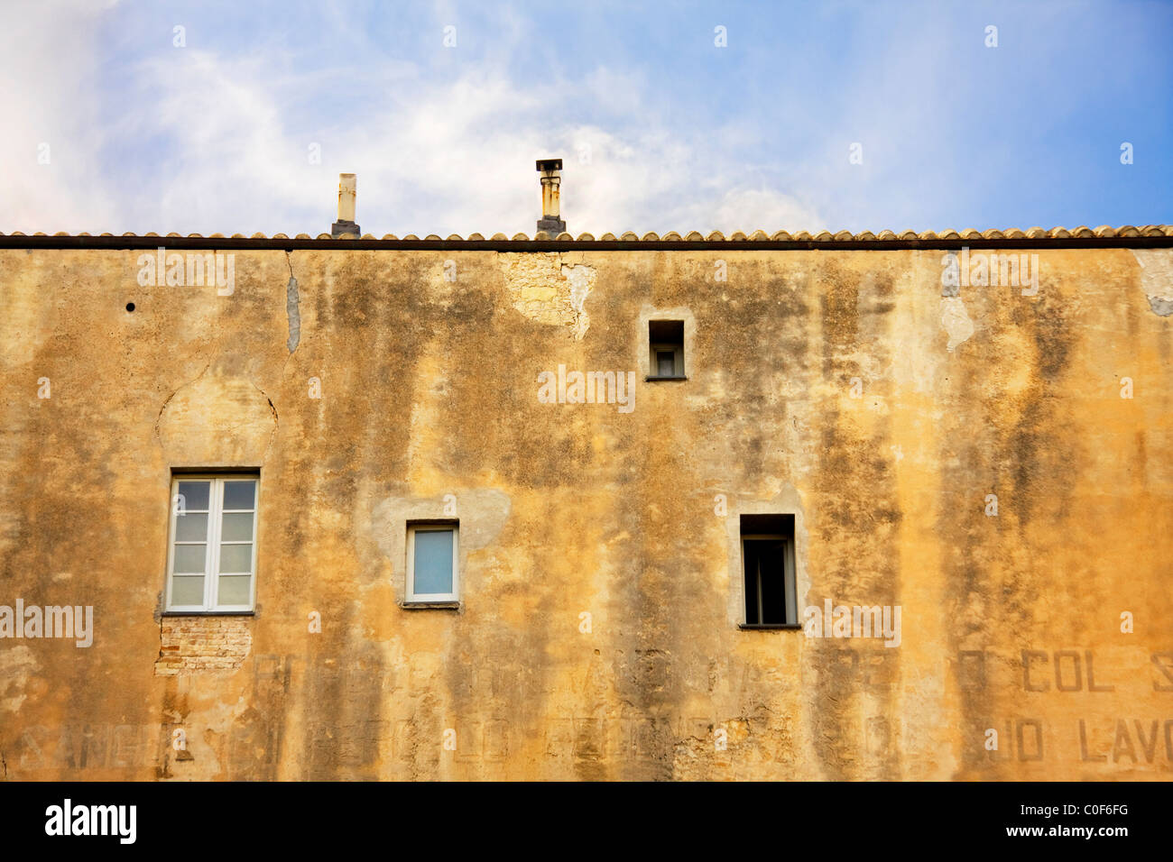 Windows on a yellow building with two chimneys in a blue sky day of Cagliari, Sardinia Stock Photo