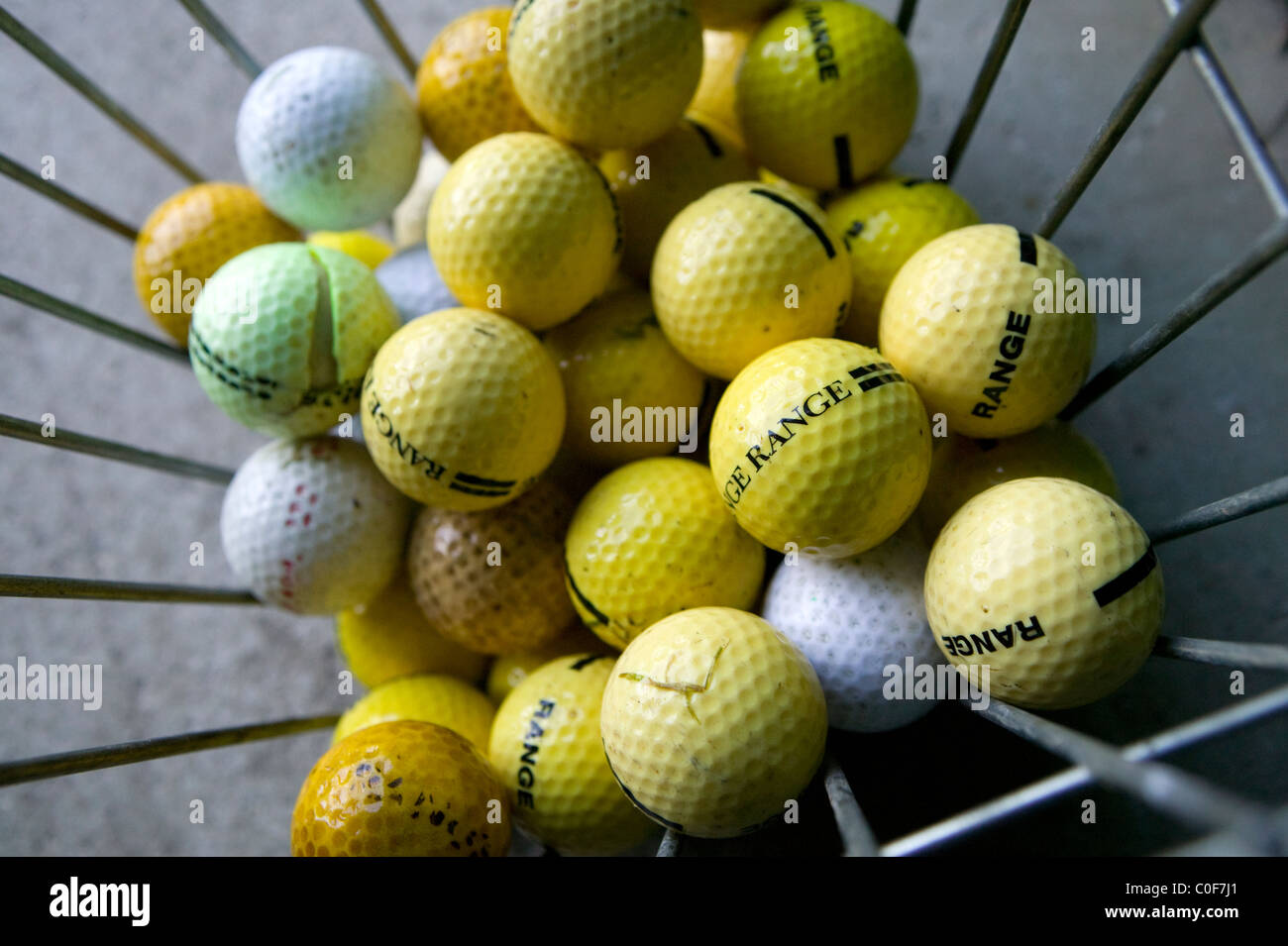 Yellow and white golf balls in a basket at a driving range Stock Photo