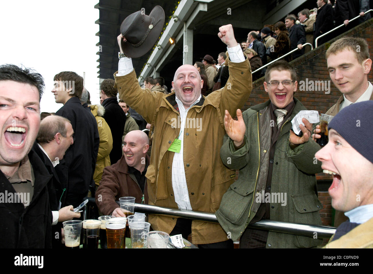 A group of men jumping for joy after watching the horse they bet on win at Cheltenham races. Stock Photo