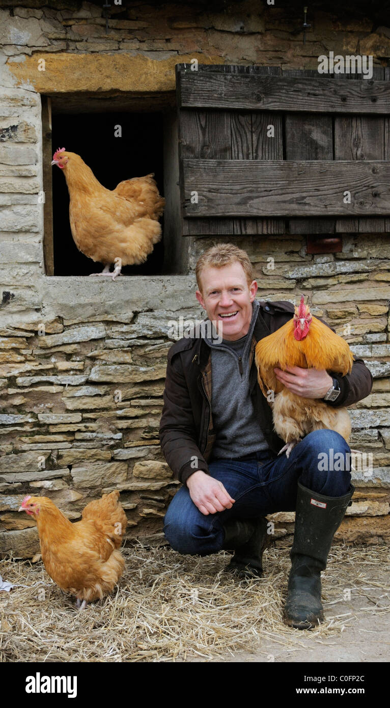 Adam Henson Cotswold farmer at Adam's farm. BBC Countryfile presenter with rare breeds Buff Orpington chicken on his shoulder Stock Photo
