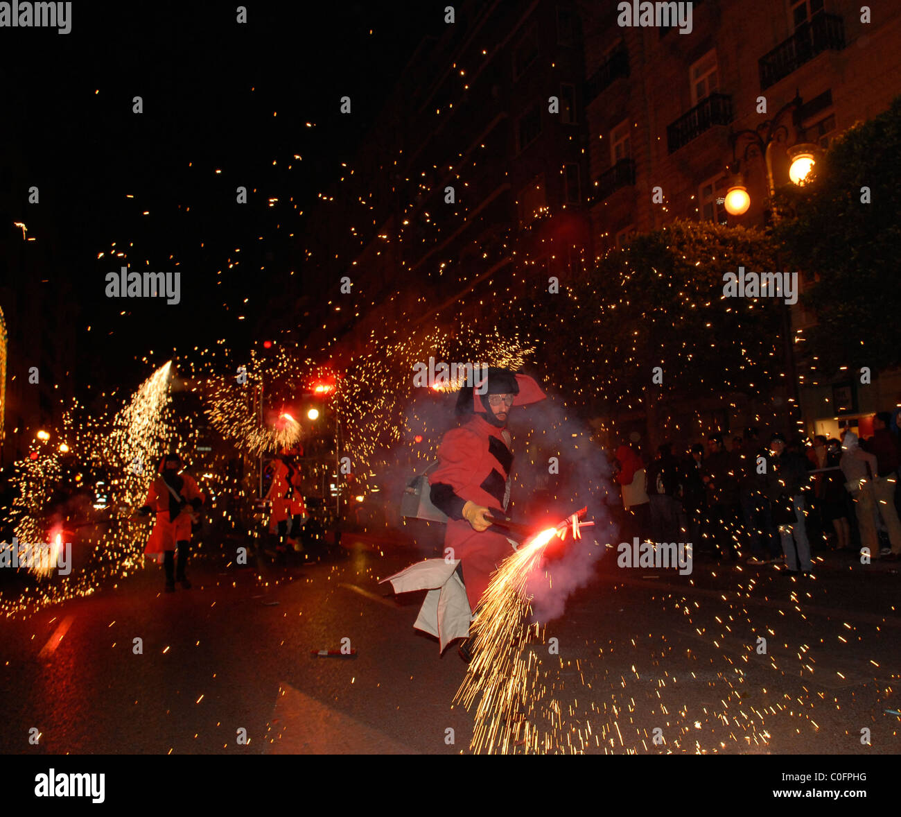 Falleros in traditional costume marching with sparklers during ...