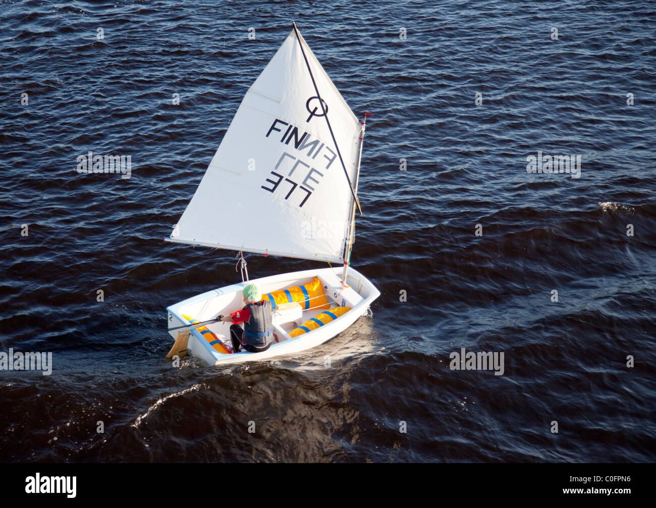 Young boy sailing alone with a small sailing boat , Finland Stock Photo