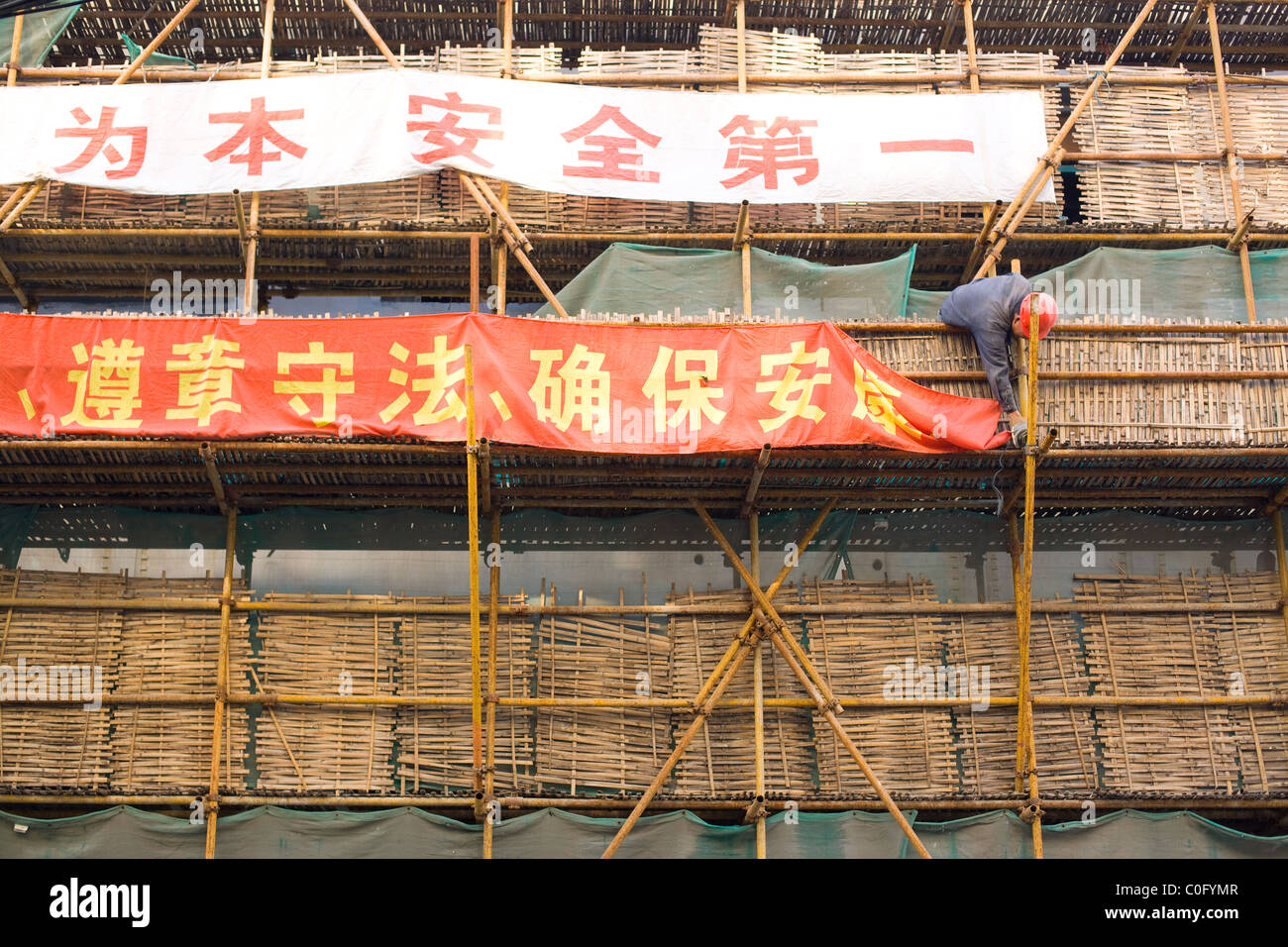 Worker in traditional Chinese scaffolding arranging a banner, Shanghai, China Stock Photo