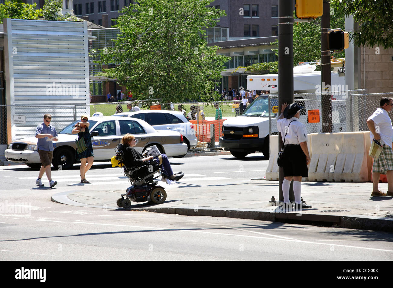 Handicapped person crossing street in wheelchair, Philadelphia, Pennsylvania, USA Stock Photo