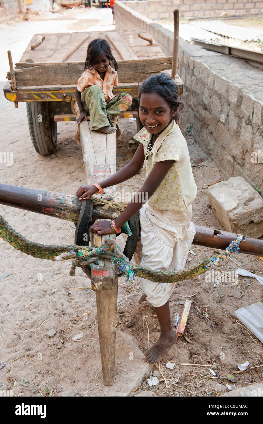 Happy young poor lower caste Indian street girls playing on a bullock cart. Sisters. Andhra Pradesh, India Stock Photo