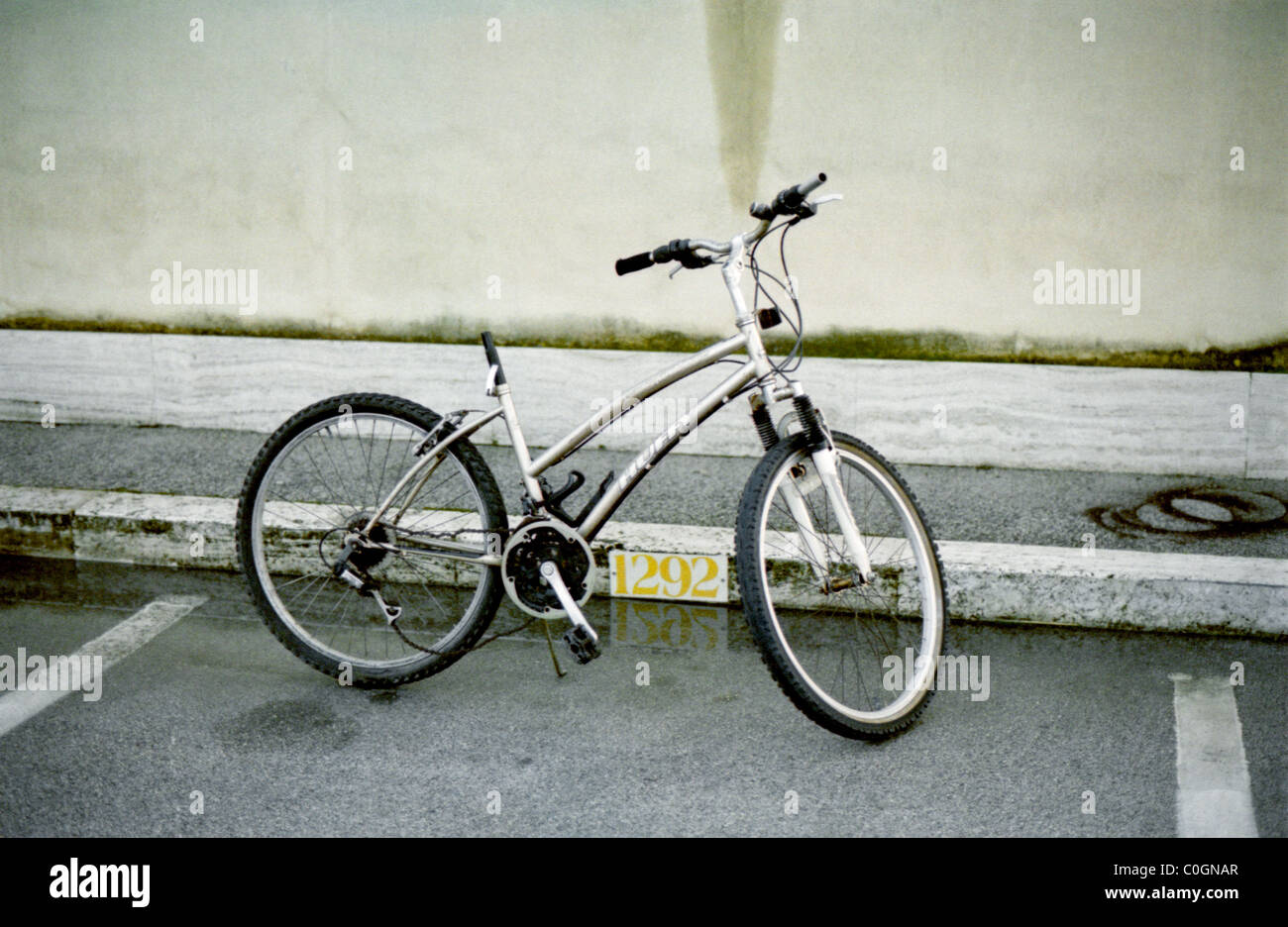 Bicycle parked on reserved car space at Ostia harbour. Missing saddle. Stock Photo