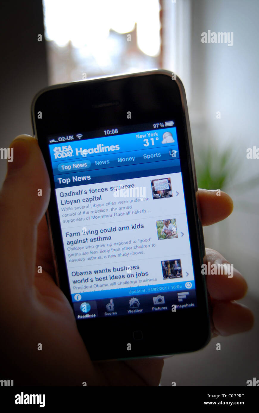 A photo illustration of a person holding an iphone 3gs, showing the USA Today News content provider app Stock Photo