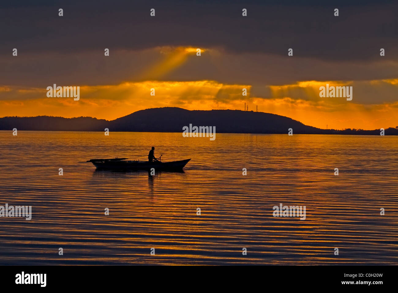 The silhouette of a fisherman with his boat in the lagoon of Amvrakikos during sunset Stock Photo