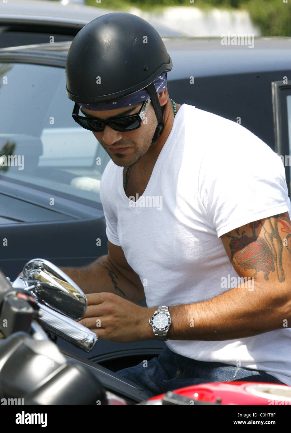 Jesse Metcalfe wearing a bandana with skull cap helmet, white t-shirt and  jeans rides off on the new Harley Davidson Rocker Stock Photo - Alamy