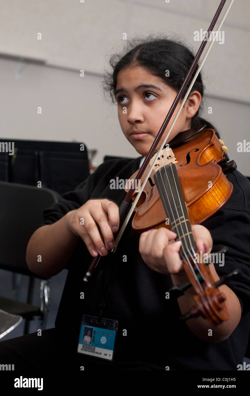 Middle school girl plays the violin during music class at the Ann