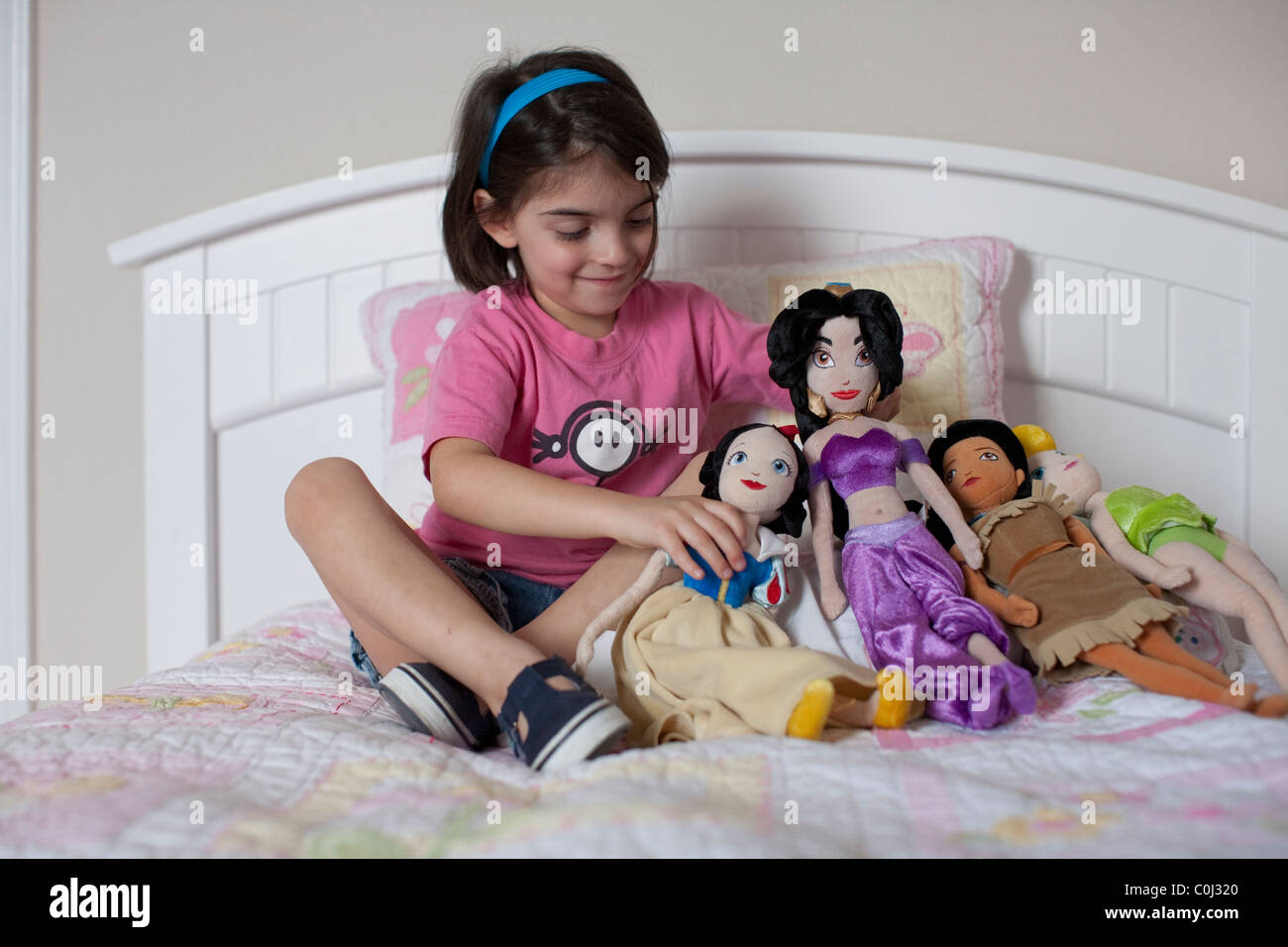 6-year-old Mexican-American girl plays with her Disney character dolls Snow White, Princess Jasmine, Pocahontas, Tinker Bell Stock Photo
