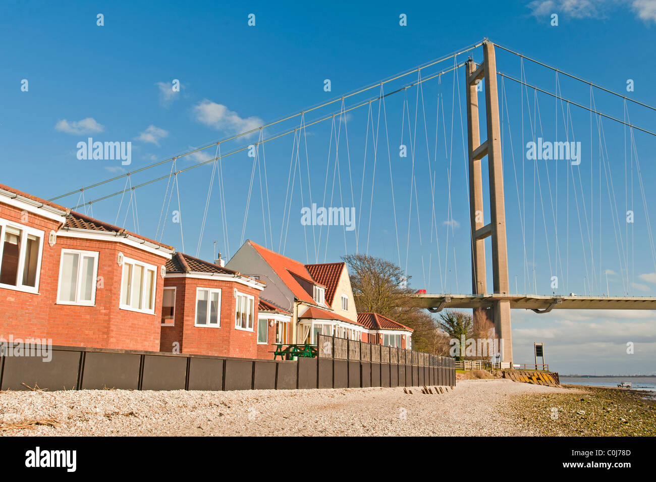 Housing community situated next to a large suspension road bridge over river Stock Photo