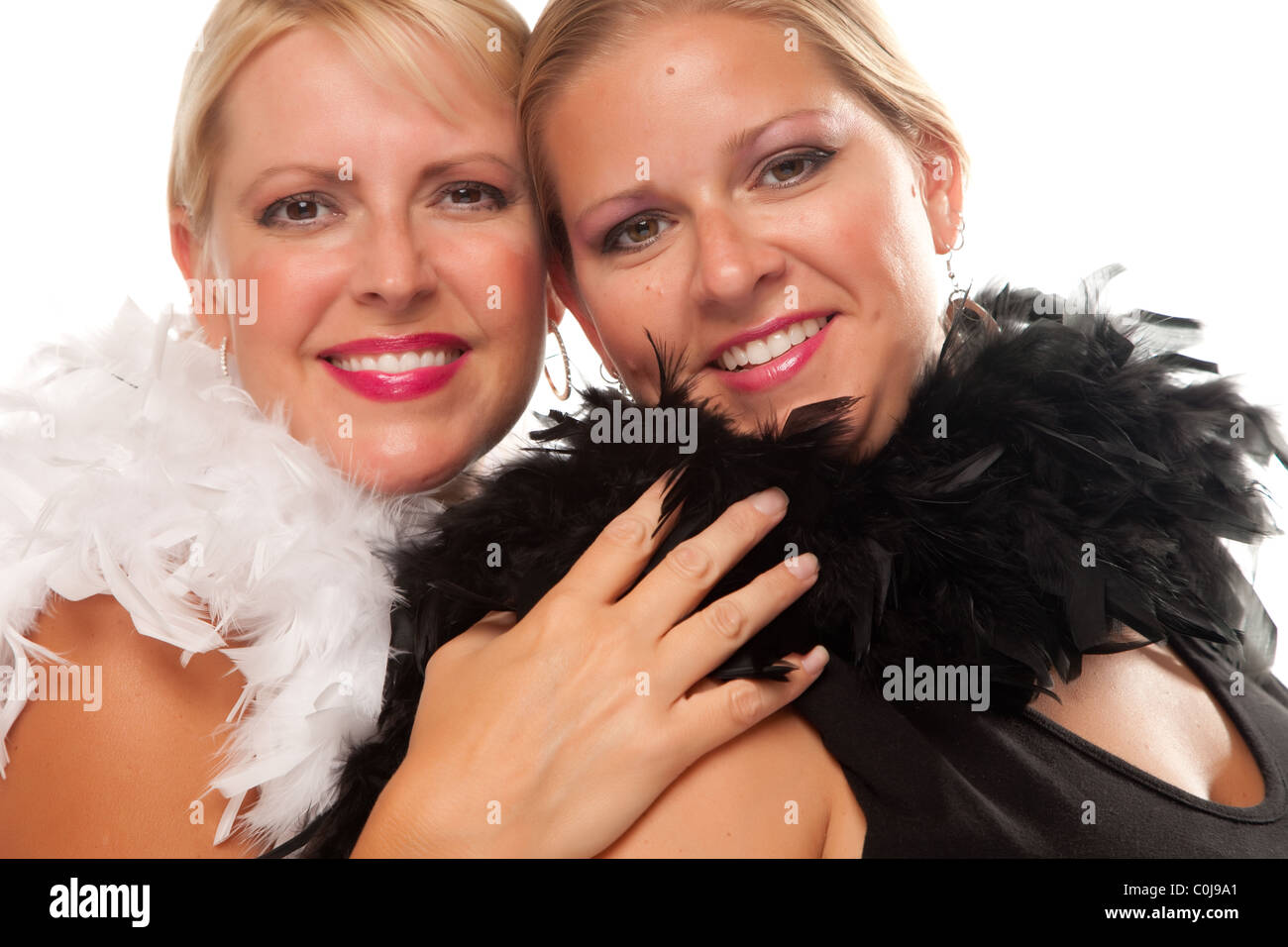 Portrait of Two Blonde Haired Smiling Girls with Feather Boas Isolated on a White Background. Stock Photo