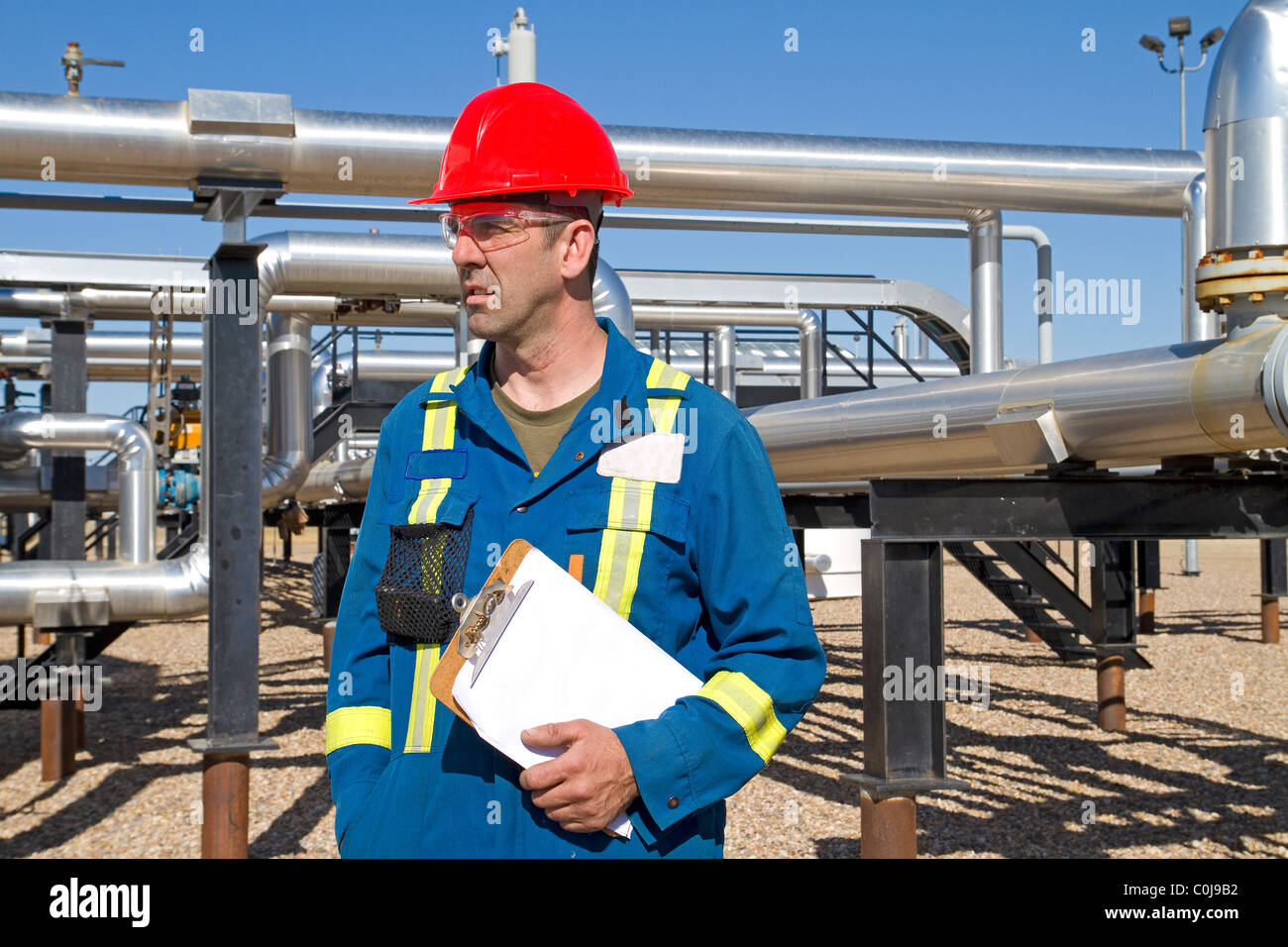 A man in full safety gear inspects and assess an upstream natural gas compressor site in alberta canada Stock Photo