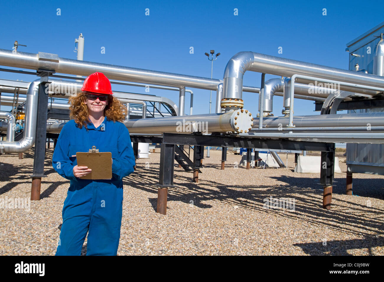 A woman in full safety gear inspects and assess an upstream natural gas compressor site in alberta canada Stock Photo