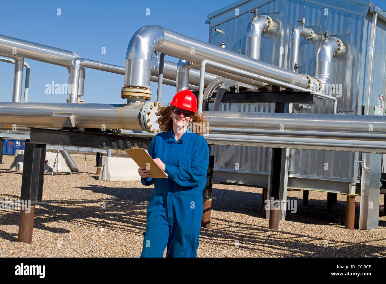 A woman in full safety gear inspects and assess an upstream natural gas compressor site in alberta canada Stock Photo