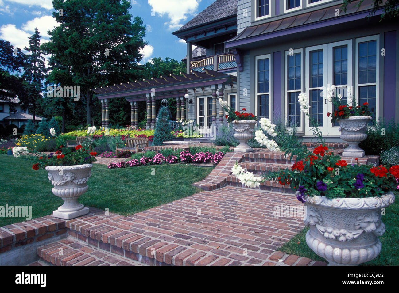 BACK GARDENS AND WALKWAY OF VICTORIAN 'PAINTED LADY' HOUSE IN MINNESOTA.  POTS OF ANNUALS IN FOREGROUND.  U.S.A. Stock Photo