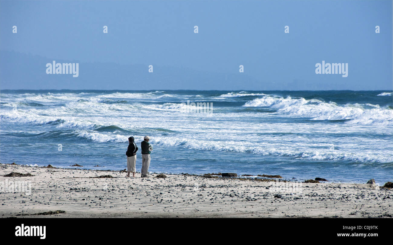 Older couple standing on California beach with Pacific Ocean in background Stock Photo