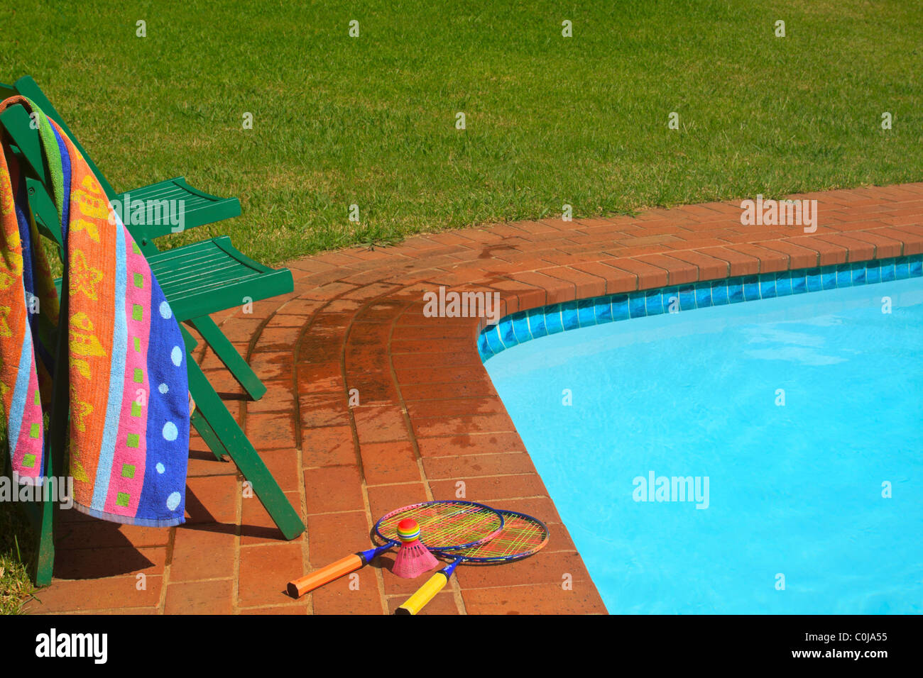 Two deck chairs and garden badminton set next to swimming pool. Stock Photo