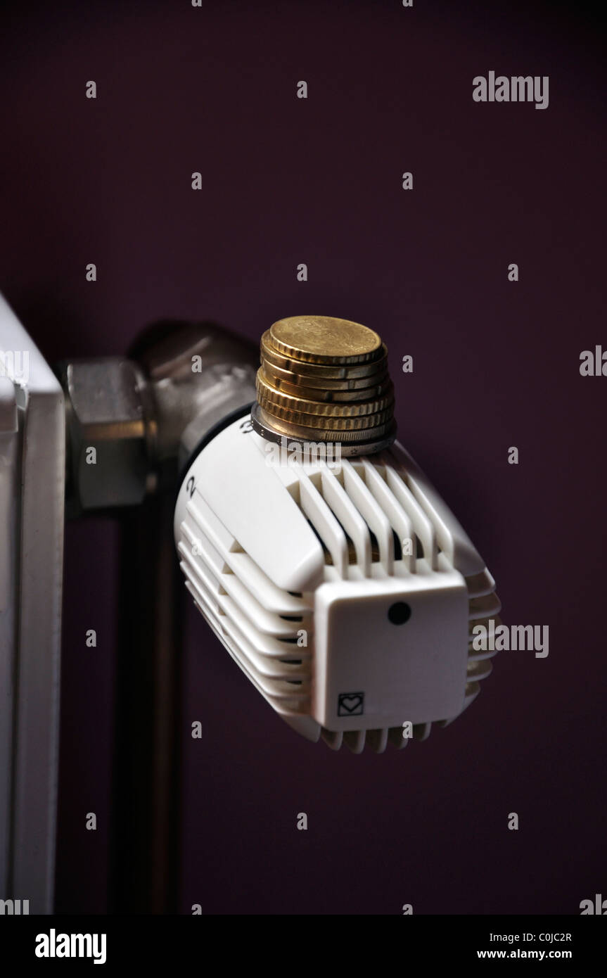 Coins on manual thermostat control on a central heating Stock Photo