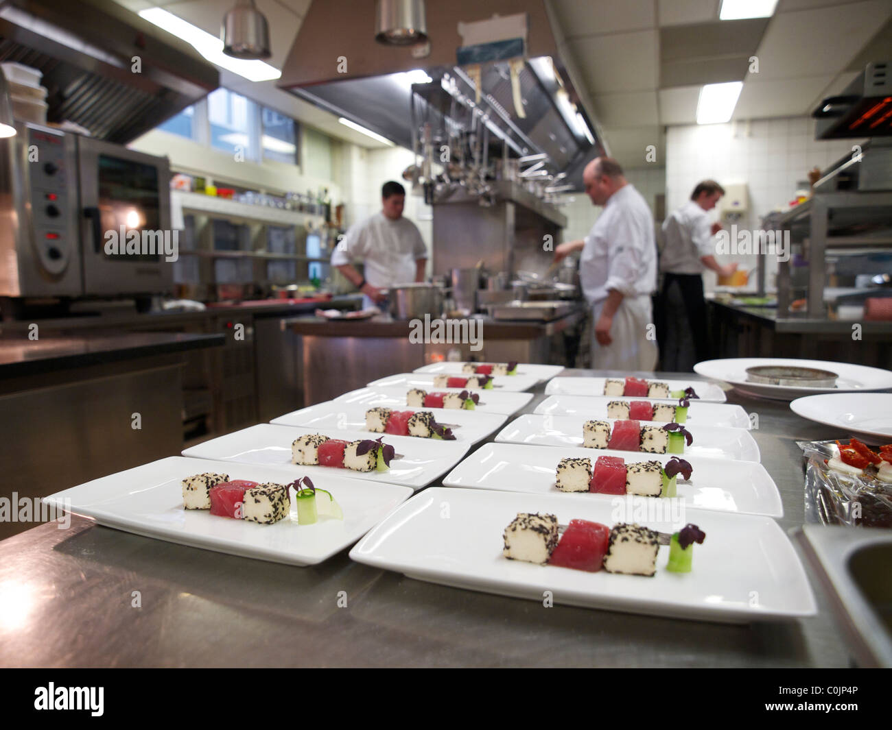 Professional restaurant kitchen with mise en place in the foreground and people working in the background Stock Photo