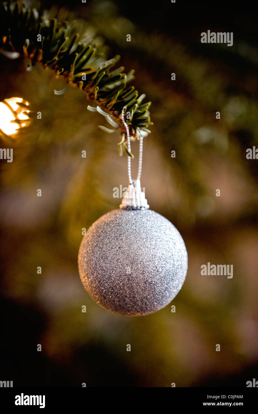 A silver glitter bauble hanging on a Christmas tree Stock Photo