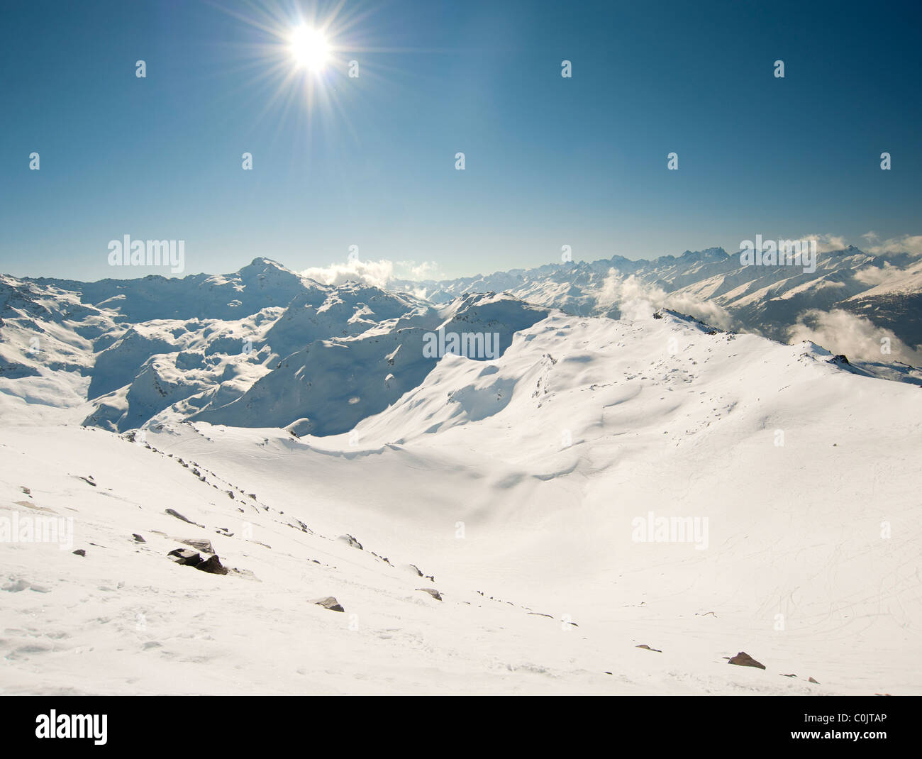 Landscape view across a snowy mountain range with the sun Stock Photo