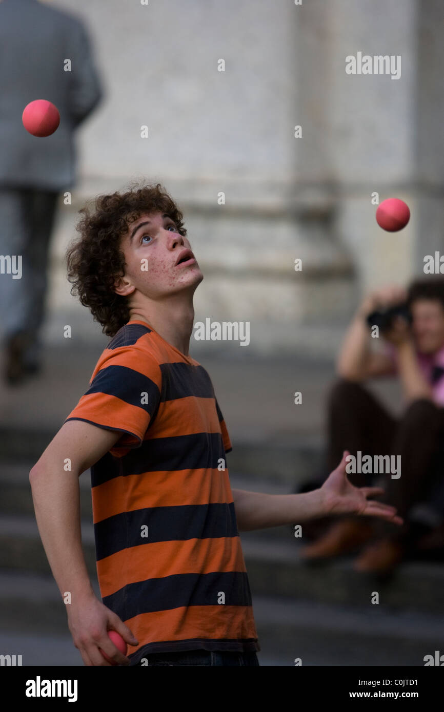 A juggler takes on three balls at the Colonne di San Lorenzo, while another photographer takes a shot too. Stock Photo