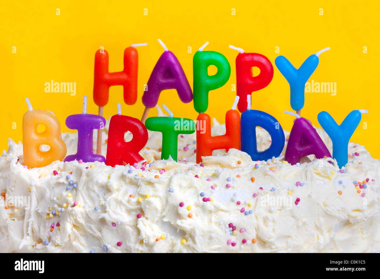 happy birthday cake shot on a yellow background with candles Stock Photo