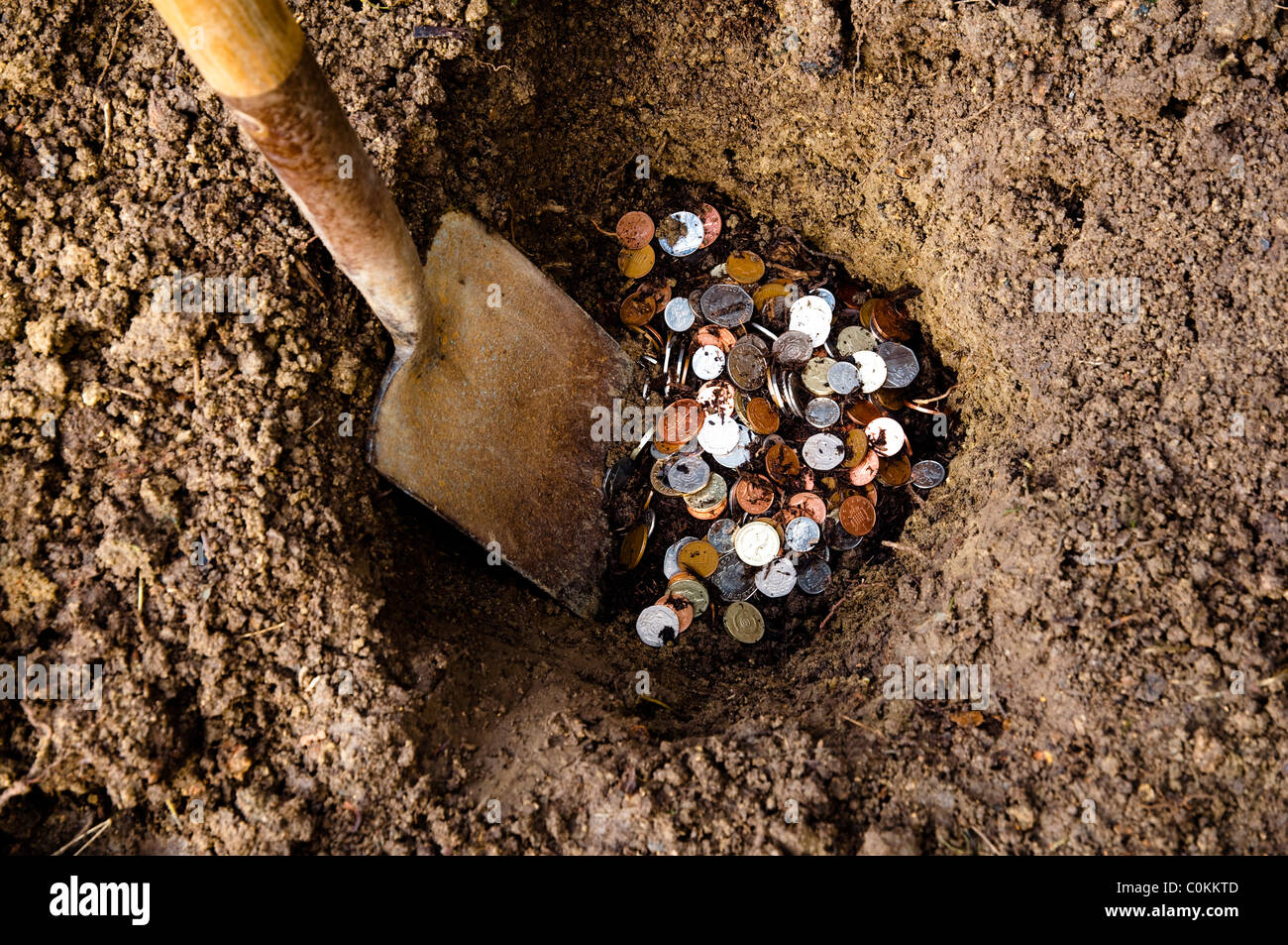 Money in a hole in the ground.  ( A money-pit,  safe-keeping for cash, or buried treasure. ) Stock Photo