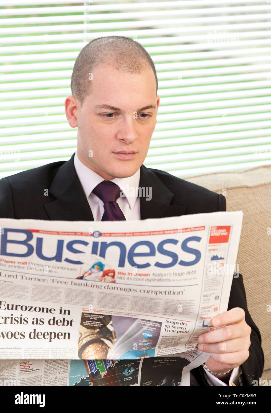 man reading business supplement in newspaper in UK Stock Photo
