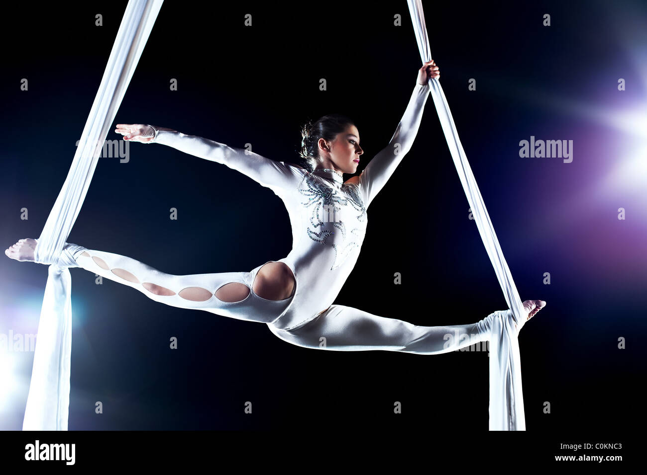 Young woman gymnast. On black background with flash effect. Stock Photo