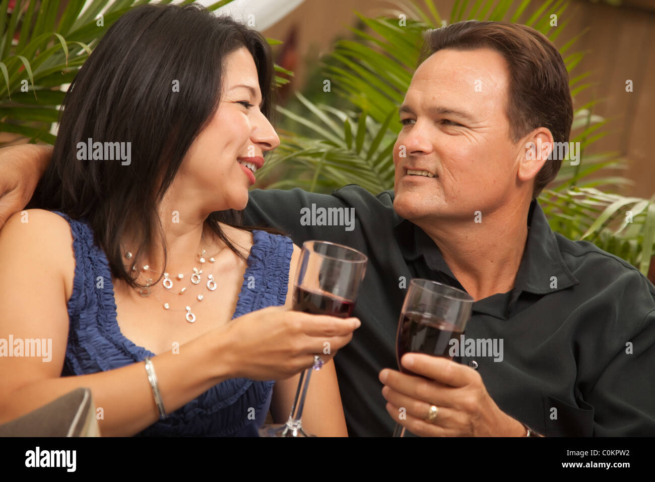 Attractive Hispanic and Caucasian Couple Drinking Wine Outside Stock