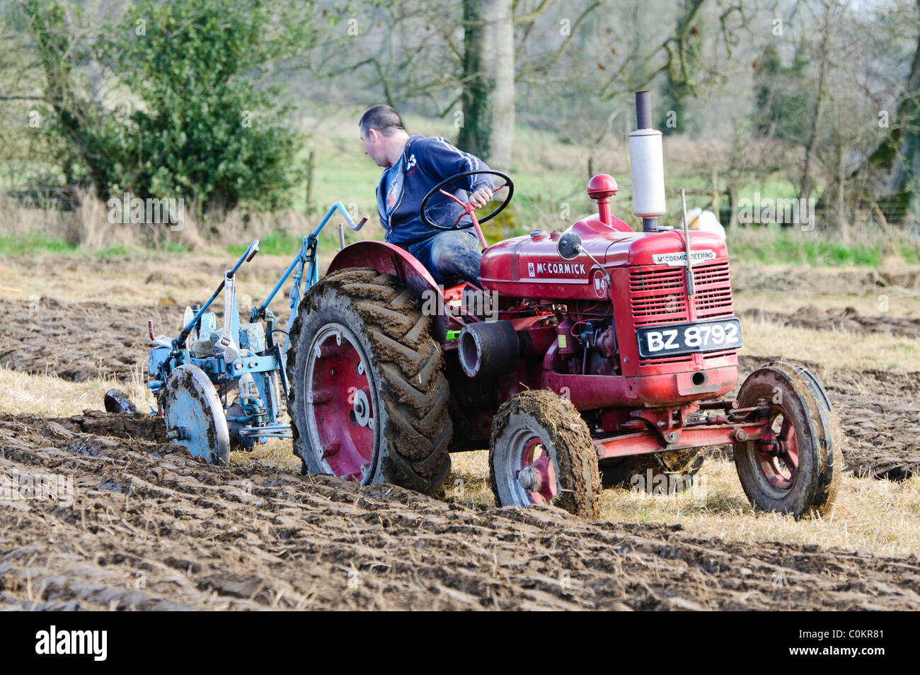 Farmer using a vintage tractor to plough a field Stock Photo