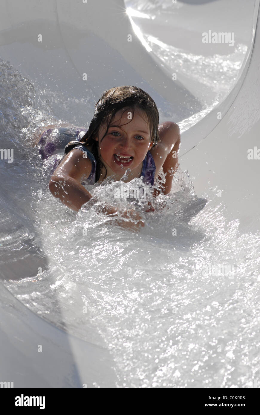 Little girl sliding head first down a water slide Stock Photo